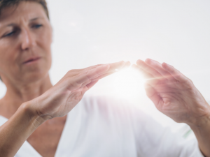 picture of hands with glowing orb representing Reiki, face in background